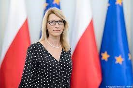 Paulina Malinowska-Kowalczyk na tle flag Polski oraz Unii Europejskiej.